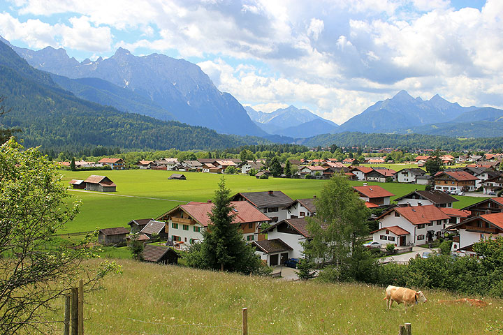 Wallgau: kylän taloja, lehmä niityllä, takana vuoria