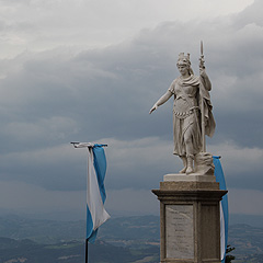 San Marinon vapaudenpatsas ja lippuja, taustalla tummat pilvet